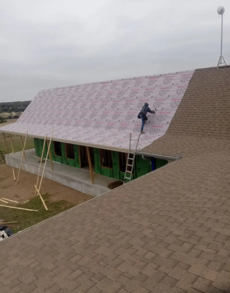 Worker preparing underlayment for a metal roof installation in Aston